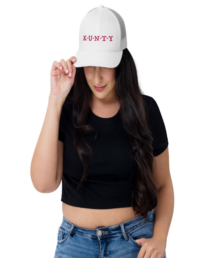 White trucker hat with K-U-N-T-Y in a bold pink text design, complete with a breathable mesh back, and an adjustable snap closure.