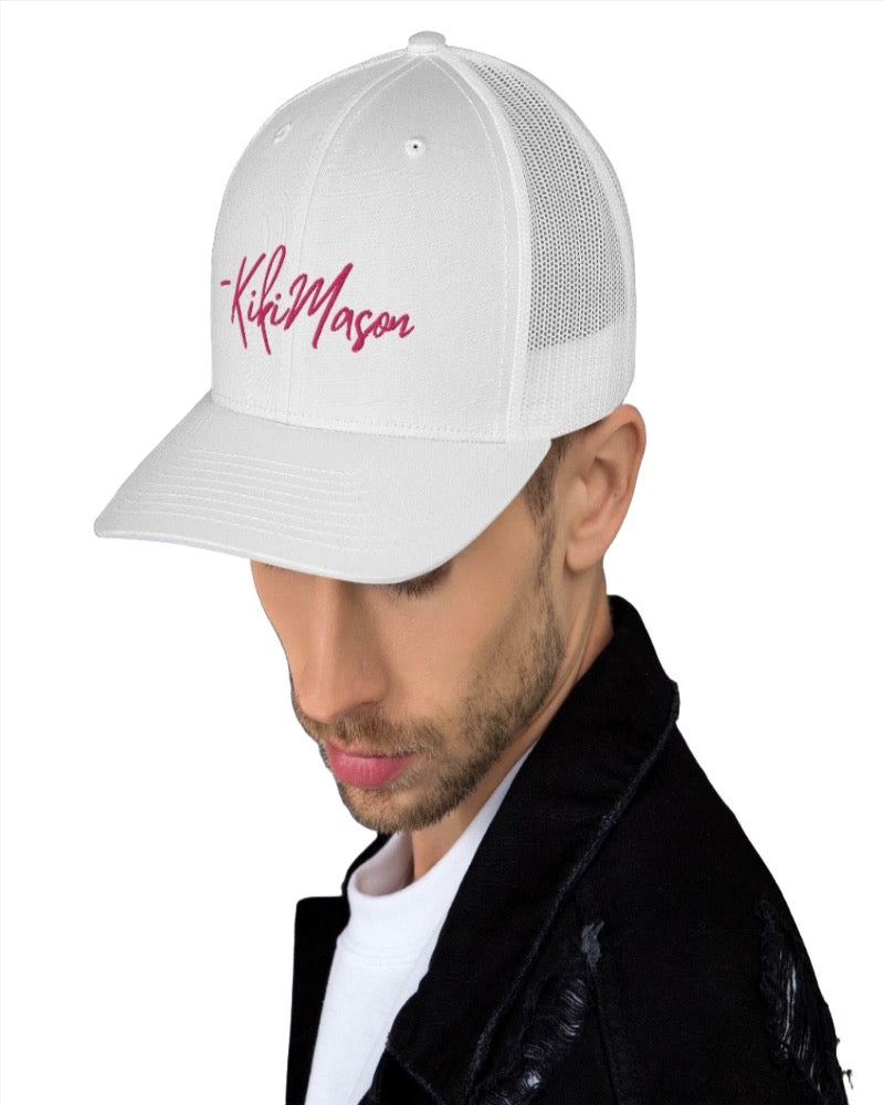 white trucker hat with Kiki Mason in a bold pink text design, complete with a breathable mesh back, and an adjustable snap closure.