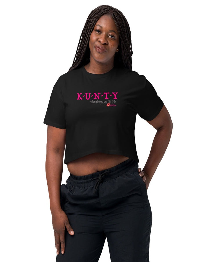 Black crop top with bold print design, “K-U-N-T-Y” in hot pink raspberry text design, and “that’s the way you like to be” in soft grey text printed on the front. Plain black back.